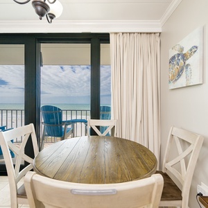 Gather around the charming table, enjoying laughter and connection while taking in stunning coastal views beyond