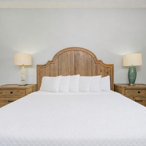 Experience restful nights in this cozy master bedroom, enveloped by soft bedding and warm wooden accents