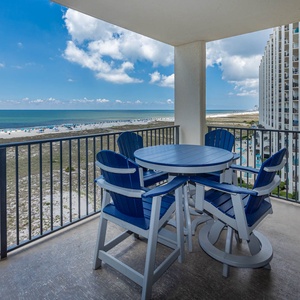 Relax on the balcony with a round table and blue chairs, enjoying sweeping views of the beach and vibrant gulf waters