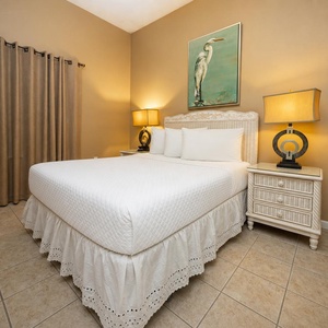 Cozy guest bedroom featuring a queen bed with decorative skirt, wicker nightstands, and soft lighting for a relaxing vibe