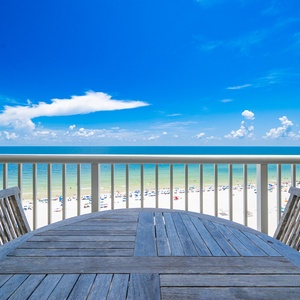 Enjoy a stunning beachfront view from the wooden table on the balcony, perfect for relaxing or dining outdoors