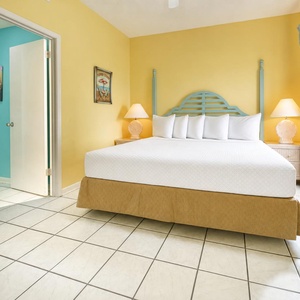 Bright yellow walls complement the king bed with a light blue headboard, creating a cheerful atmosphere in this guest bedroom
