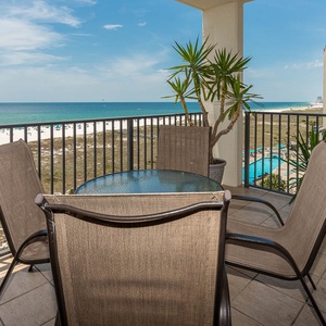 Relax on the balcony with a glass table and chairs, overlooking the tranquil beach and inviting turquoise waters