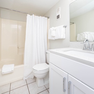 The bathroom features a clean design with a spacious vanity, fresh towels, and a shower/tub combo for a refreshing experience