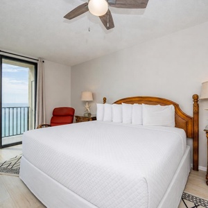 Relax in this master bedroom featuring a king bed, a cozy chair, and the sights and sounds of the beach from your room