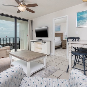 This inviting living area features a large TV, comfortable seating, and a stunning beachfront view through expansive windows