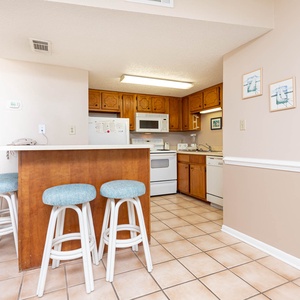 This kitchen features wooden cabinetry, essential appliances, and a cozy breakfast bar, perfect for casual dining