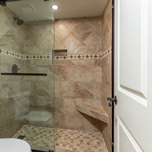 Master bath featuring a walk-in shower with elegant tile work and a built-in bench for comfort and convenience