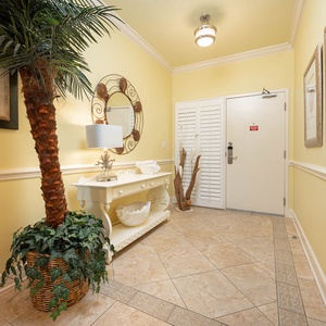 Step into a welcoming entryway featuring tropical decor, a stylish console table, and warm yellow walls