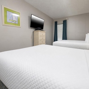 The guest bedroom features two comfortable full beds, a TV, and bright decor, perfect for a relaxing getaway