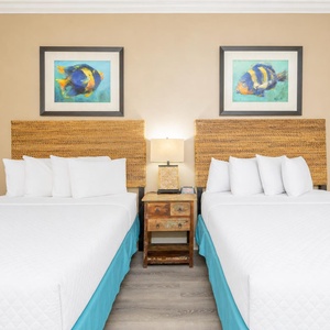 Discover tranquility in this inviting guest room, featuring two queen beds and beautiful coastal artwork
