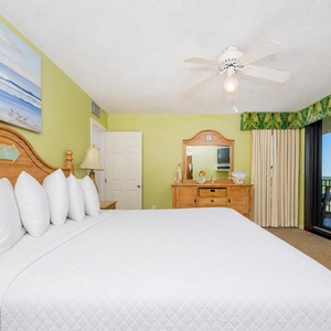 Inviting master bedroom featuring a plush king bed, tropical decor, and access to a scenic balcony view