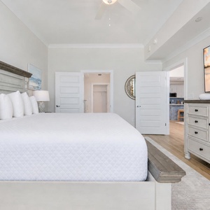 Relax in this master bedroom featuring a king bed, soft pillows, and a large TV