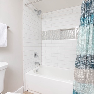 Geust bathroom featuring a tub/shower combo with a colorful shower curtain and fresh towels neatly arranged nearby