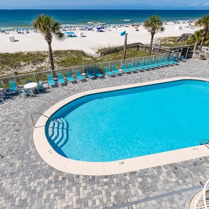 This inviting view showcases a sparkling pool surrounded by lounge chairs, with a stunning beach just steps away