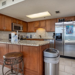 Warm wood cabinetry complements the granite countertops in this modern kitchen, featuring a breakfast bar with seating
