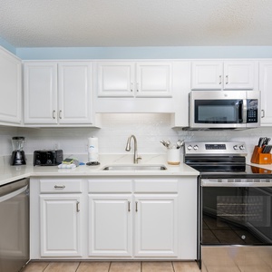 Bright white cabinetry and sleek countertops complement a modern kitchen with stainless appliances and a cozy atmosphere