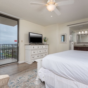Relax in this inviting master bedroom with a plush bed, TV, and sliding doors leading to a scenic balcony view