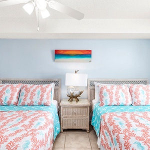 Brightly decorated guest bedroom featuring two double beds, complemented by a coastal-themed artwork