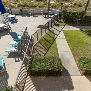 Relax by the pool area featuring turquoise lounge chairs, shaded tables, and a barbecue grill, surrounded by lush greenery