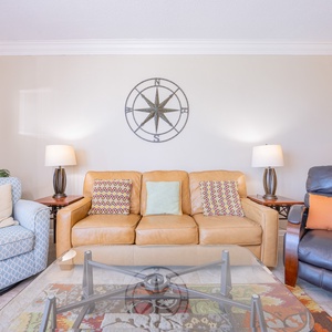 Relax on the leather sofa with decorative pillows, surrounded by soft lighting and coastal decor accents