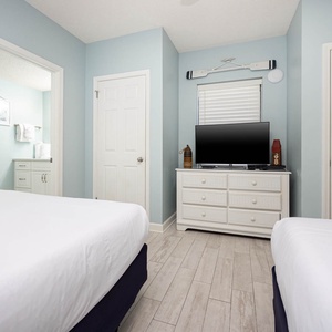 Enjoy restful nights in this relaxing guest room with two double beds, a TV, and soft blue walls that create a calming vibe