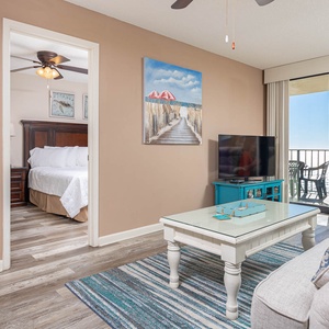 Living area with a TV, beach view balcony, and cozy furnishings with a queen sofa-sleeper for a relaxing getaway