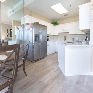 Bright and airy kitchen area featuring white cabinetry, a breakfast bar, and a dining space with stylish wooden chairs