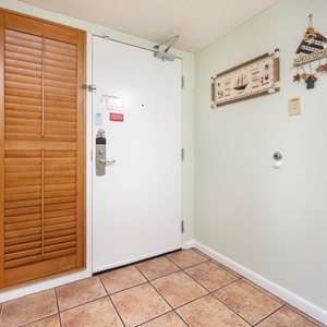 The entryway features a white door with a security lock, wooden shutter doors, and decorative nautical wall art