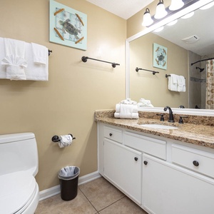 Refresh in the stylish guest bathroom featuring a granite countertop, ample towels, and a decorative coastal theme