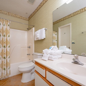 Refresh in this guest bathroom featuring a large vanity, ample towels, and a relaxing tub-shower area for your comfort