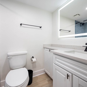 Guest bath featuring a sleek vanity with a large mirror, blue tiled wall, and a tub/shower combo for a refreshing experience