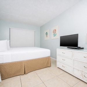 This bedroom features a comfortable bed, stylish decor, and a TV, perfect for relaxing after a day at the beach