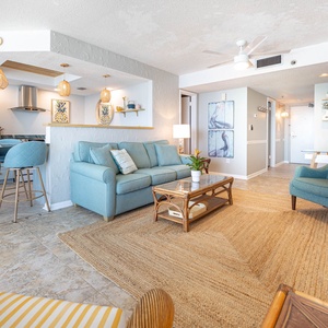 The living area features a cozy blue sofa with full sleeper, coffee table, and stylish beach decor