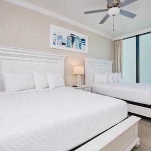 Relax in this guest bedroom featuring two queen beds, soft linens, and stunning beach views
