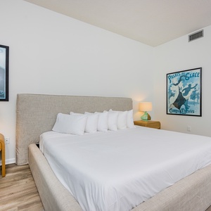 Guest bedroom featuring a plush king bed, two twin bunks, stylish artwork, and warm lighting for a cozy retreat