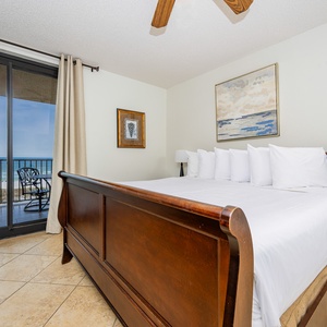 Relax in the serene master bedroom featuring a king bed, coastal artwork, and sliding doors that open to beautiful views