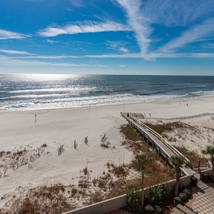This beachfront balcony view showcases the serene sandy shore and gentle waves, perfect for relaxation and enjoyment