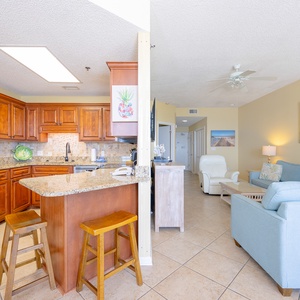 The kitchen features rich wooden cabinetry, a granite countertop breakfast bar with seating, and stainless appliances