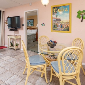 The cozy living area features a blue sofa, a TV, and a dining table with beach-themed decor, perfect for relaxation and meals