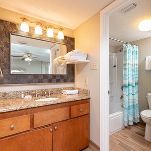 Master bath featuring a granite countertop with a large mirror, a tub/shower combo, and decorative towels neatly arranged