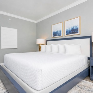 Relax in this inviting guest bedroom featuring a spacious king bed, stylish decor, and soothing artwork