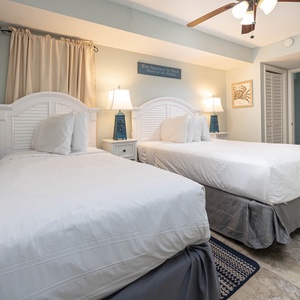 This bedroom features two comfortable beds, soft lighting, and beach-themed decor for a relaxing stay