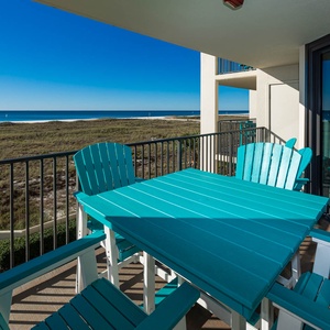 Bright turquoise outdoor furniture on the balcony offers a perfect spot to enjoy views of the beach and gulf waters