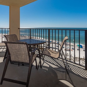 Enjoy a relaxing moment on the balcony with beach views, featuring a table and chairs for outdoor dining