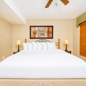 The bedroom features a plush king bed, warm lighting, and tasteful decor, perfect for a restful getaway
