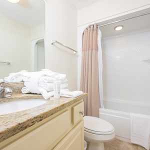 Guest bathroom featuring a granite countertop, soft towels, and a tub/shower combo for a refreshing experience