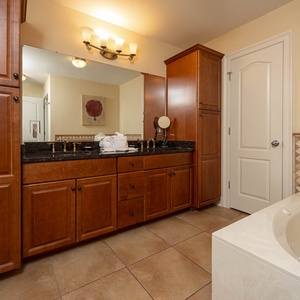 The master bath features elegant wood cabinetry, a vanity with a large mirror, walk-in shower, and a relaxing jetted tub