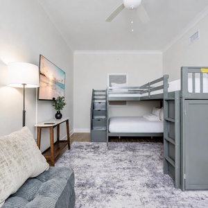 Cozy guest bunk room featuring a TV, and two stylish loft bunk twins over a double bed