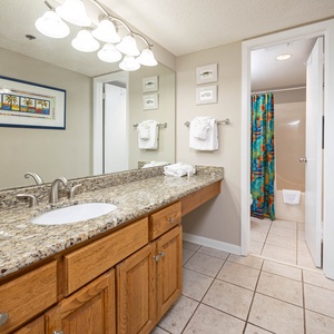 Refresh in this spacious master bath, featuring a granite countertop, colorful shower curtain, and ample storage